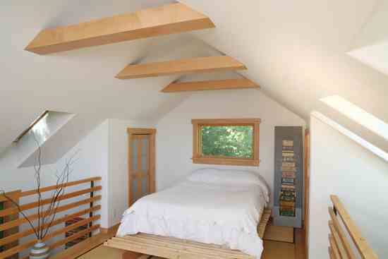 
A sloping ceiling line with exposed beams lends interest and allows the bedroom décor to stay minimal. Skylights along both sides of the bedroom create the feeling of sleeping under the stars.
